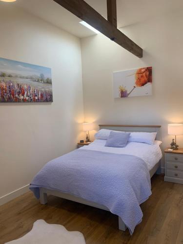 达灵顿Barford barn holiday cottage的卧室配有一张床,墙上挂有绘画作品