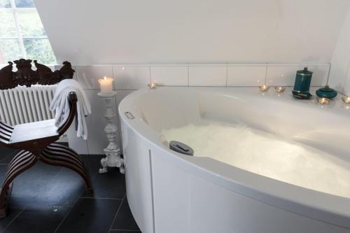 穆尔滕宫明兴维勒酒店的浴室设有白色浴缸及椅子