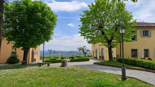 卡尔米尼亚诺Dépendance in Villa Albachiara e Primaluce的一座带长凳和树木的公园和一座建筑