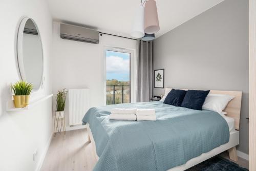 波兹南Stara Cegielnia Lake View Apartment by Renters Prestige的白色卧室设有蓝色的床和窗户