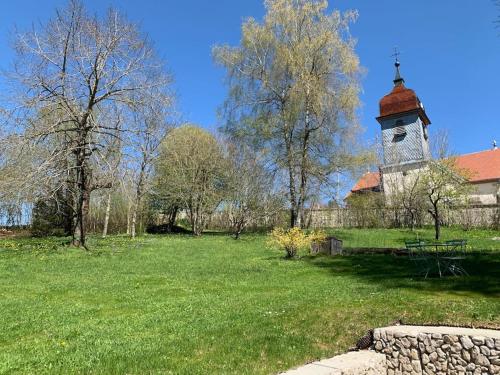 MontperreuxAncienne ferme comtoise 4 étoiles, 11 personnes Lac St-Point/Mont d'Or的一座教堂,在田野上建钟楼