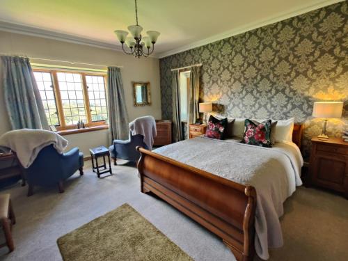 波洛克Luxury Bed And Breakfast at Bossington Hall in Exmoor, Somerset的一间卧室配有一张大床和一把椅子