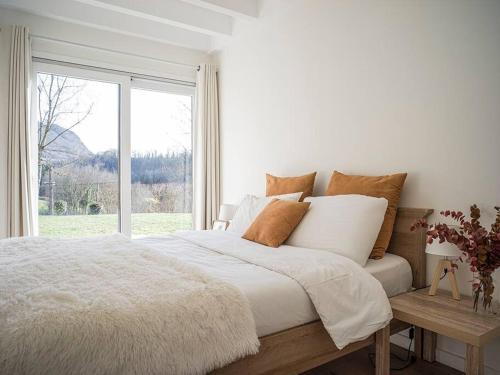 Nâves-ParmelanVenez Chez Vous - Le Cocon du Parmelan的白色的卧室设有一张大床和一个窗户