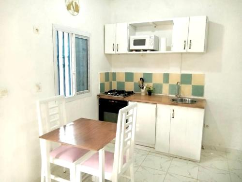 杜阿拉Gêna house的厨房配有白色橱柜、桌子和微波炉