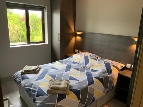 戈尔韦Small,smart,tidy 2 bed apartment的一间卧室配有一张色彩缤纷的床和两张毛巾