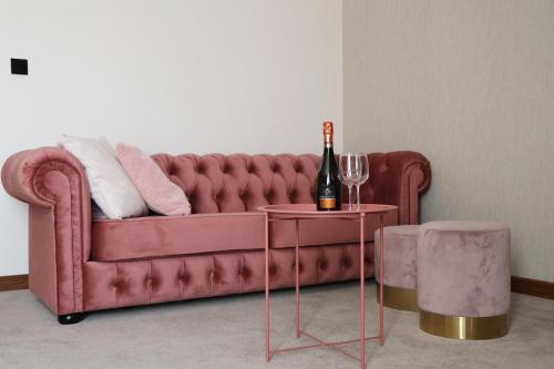 沃姆扎M&W Hotel Wronowski的一张红色沙发,桌子上放着一瓶葡萄酒