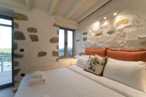 迈索尼Afentiko Pigadi的一间卧室设有一张带石墙的大床