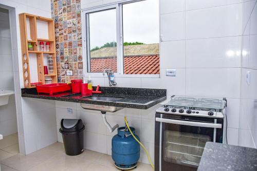索莱马Casa com Wi-Fi a 400 metros da Praia Maracanã-SP的厨房配有水槽、炉灶和窗户。