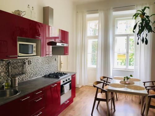 布拉格Adam&Eva Rooms的厨房配有红色橱柜和桌椅