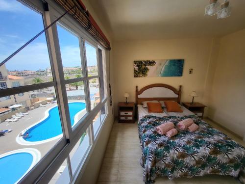 卡亚俄萨尔瓦赫Apartment next to Ajabo Beach Pool & Ocean view的一间卧室配有一张床,享有游泳池的景色