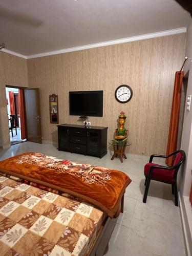 瓦拉纳西Kaashi Flora (Full Villa - 5 Bedrooms)的卧室配有一张床,墙上挂着一个钟