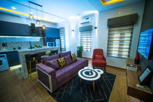 KubwaHortencia by Durudove Apartments的一间带紫色沙发的客厅和一间厨房