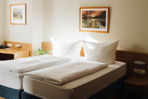 多伦特拉普贝加塔兰德汉斯酒店的一间卧室配有带白色床单和枕头的床。