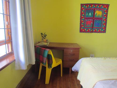 开普敦Victorian Woodstock的一间卧室配有一张桌子、一把椅子和一张床