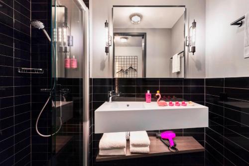 达姆施塔特Moxy Darmstadt的浴室配有白色水槽和淋浴。