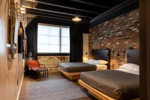 纳什维尔Moxy Nashville Downtown的一间卧室设有两张床和砖墙