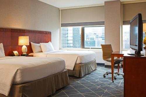 纽约纽约曼哈顿/市中心东区庭院酒店的酒店客房设有两张床、一张桌子和一台电视。