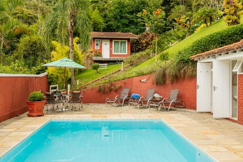 伊泰帕瓦Su Paradise Chalés e Suítes的一个带桌椅的游泳池和一个房子