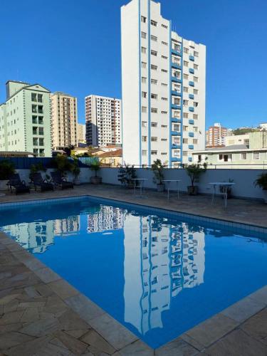 波苏斯-迪卡尔达斯Hotel Lux的一座游泳池,位于一些高楼前