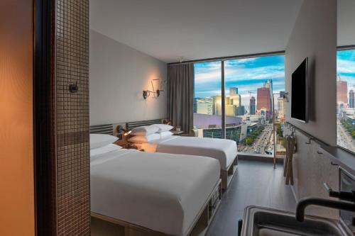 洛杉矶Moxy Downtown Los Angeles的酒店客房设有两张床和大窗户。