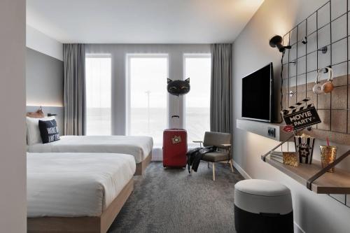 圣艾修伯里Moxy Lyon Airport的一间酒店客房,设有两张床和电视