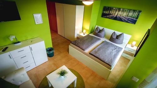 萨勒河畔瑙姆堡Pension Village的小房间设有一张带绿色墙壁的床