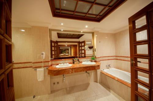 亚松森Granados Park Hotel的浴室设有2个水槽、浴缸和镜子