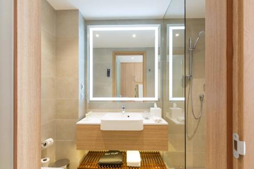 巴尼亚卢卡Courtyard by Marriott Banja Luka的一间带水槽、镜子和淋浴的浴室