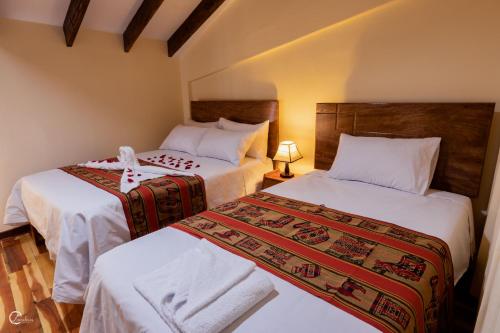库斯科Quechua Hostal Recoleta的一间卧室配有两张带白色床单的床