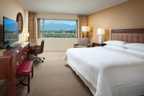 安大略安大略机场喜来登酒店的配有一张床、一张书桌和一扇窗户的酒店客房