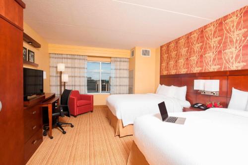 皮奥里亚皮奥里亚市中心万怡酒店的酒店客房设有两张床、一张桌子和一台电视。