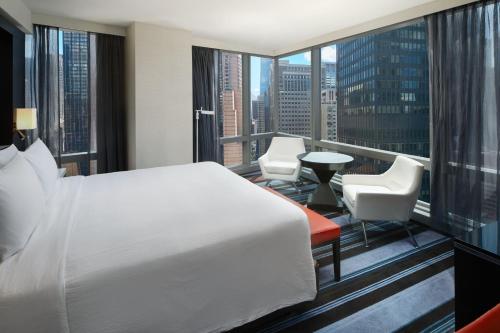 纽约纽约曼哈顿/中央公园万豪万怡酒店的一间卧室配有一张床,阳台配有桌椅