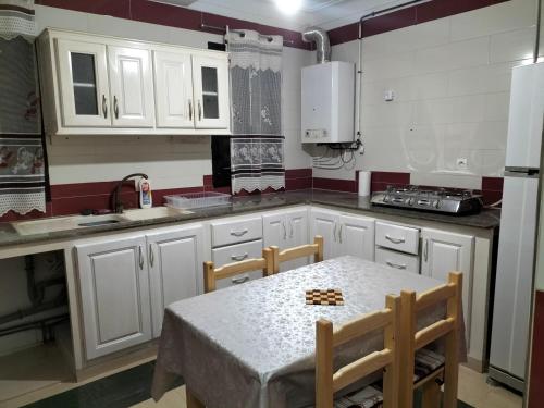 阿尔及尔MAÏS的厨房配有白色橱柜和桌椅