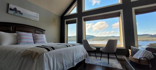 科纳布鲁克Coastal Lookout Suites的一间卧室配有一张带两把椅子的床和大窗户