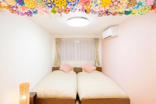 东京CuteFamilyHouse! 3LDK 6minShinjuku 3minJRsta Cozy,Fun,Bright! KidsFree Under6yrs的一间设有两张床的客房,天花板上有一幅画