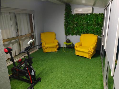 查韦斯Casa Valadim的一间设有两张黄色椅子的客房,铺有绿色地毯