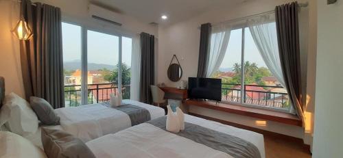 万荣VangVieng Crystal Boutique Hotel的酒店客房设有两张床和大窗户。