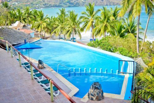 锡瓦塔塔内霍卡塔利娜海滩度假酒店的一座种植了棕榈树和大海的大型蓝色游泳池