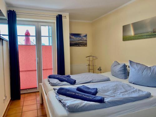 博尔滕哈根2 Zimmer Appartement Poseidon的客房内的两张床和蓝色枕头