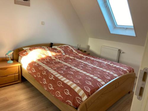 佐内贝克Het Zonnetje Zonnebeke的一间卧室配有一张带红色棉被的床和窗户。