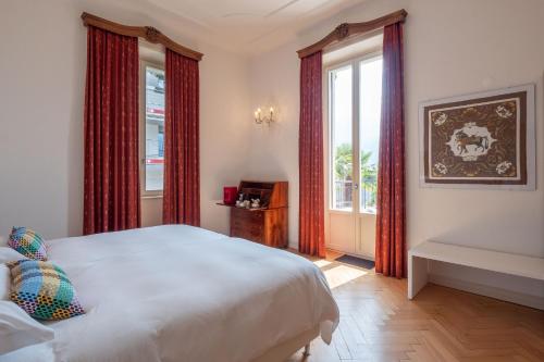 洛迦诺Villa by @ Home Hotel Locarno的卧室配有白色的床和红色窗帘