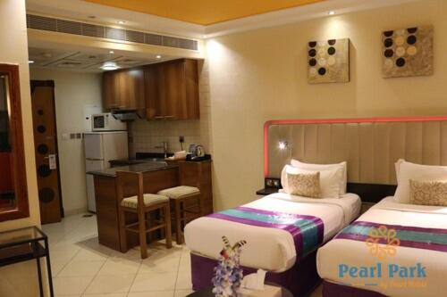 迪拜Pearl Executive Hotel Apartments的酒店客房带两张床和厨房