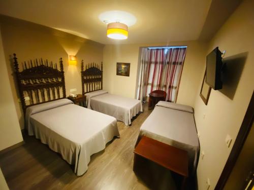 普韦布拉桑纳比亚Hotel Gran Casona de Sanabria的酒店客房设有两张床和电视。
