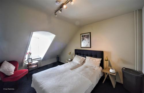 马斯特里赫特city Apartment "Op de Thermen"的一间卧室配有一张大床和一张红色椅子