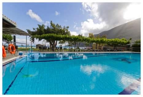 瓦西利基Porto Fico Hotel的一个大蓝色游泳池,背景是一座山