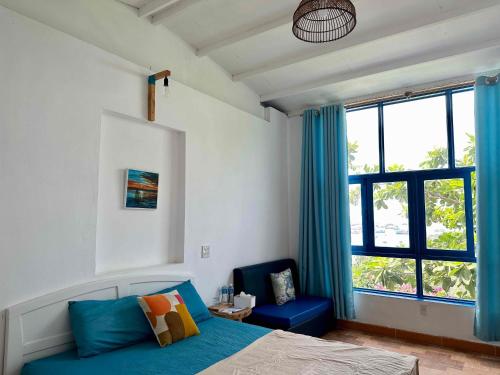 美奈IRINI Boutique Homestay Mui Ne的一间卧室配有一张床、一把蓝椅和一个窗户。