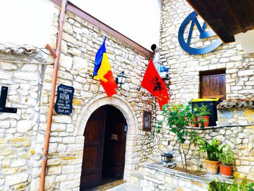 培拉特Guva Mangalem Hotel Restaurant的一面有旗帜的石头建筑