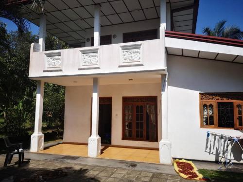 本托塔Sithu Guesthouse的白色的房子,设有门廊和阳台