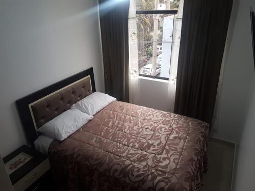 塔克纳Queen's Residence VIP的一间卧室配有一张带棕色床罩的床和窗户。
