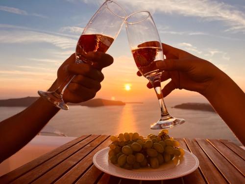 易莫洛林Esmi Suites Santorini的两人拿着酒杯和一盘食物